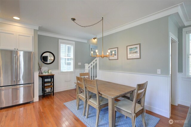 dining area featuring a wainscoted wall, light wood finished floors, stairway, and crown molding