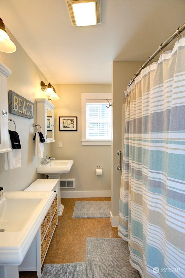 bathroom featuring a shower with curtain, baseboards, and a sink