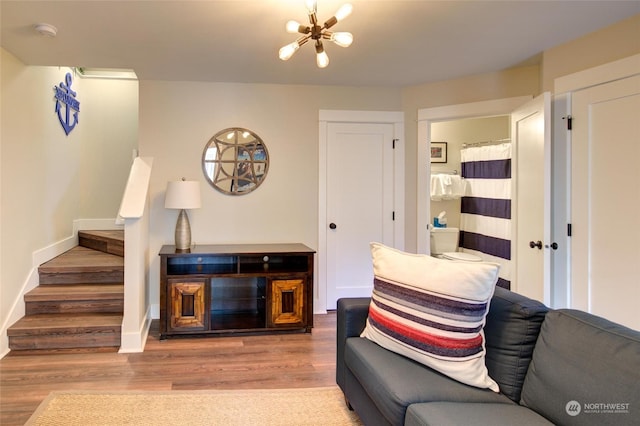 living room with baseboards, stairway, wood finished floors, and an inviting chandelier