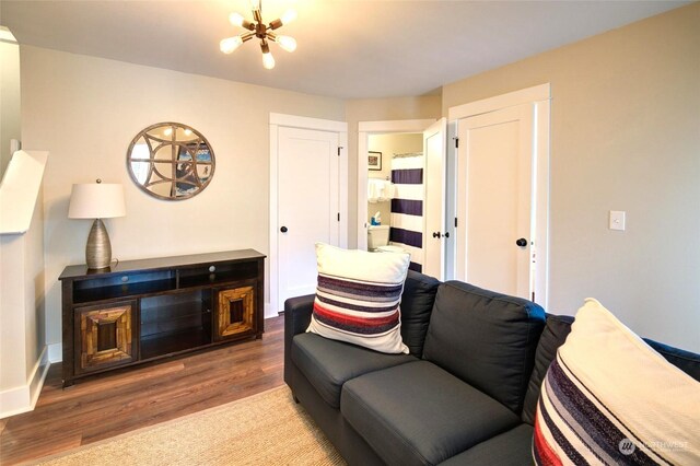 living room with a chandelier, baseboards, and wood finished floors