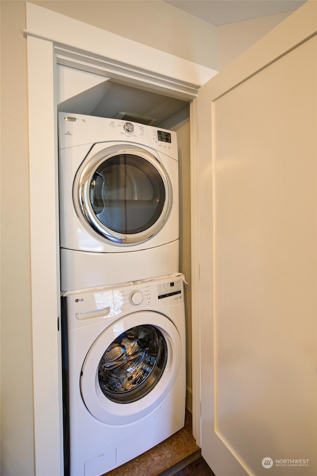 clothes washing area featuring laundry area and stacked washing maching and dryer