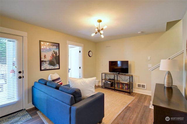 living area with dark wood-style flooring, visible vents, baseboards, and an inviting chandelier