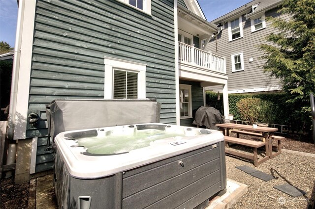 view of patio featuring grilling area, a balcony, and a hot tub