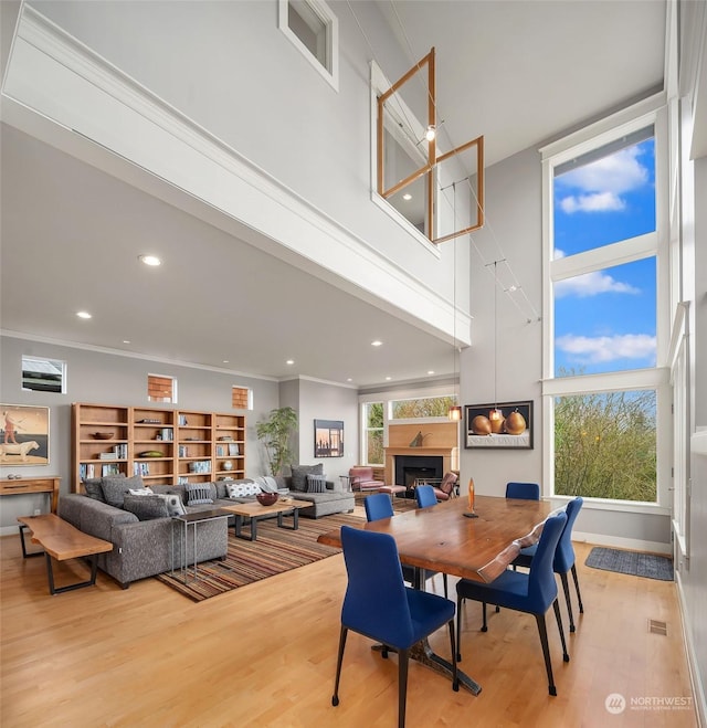 dining room featuring crown molding, light hardwood / wood-style flooring, and a towering ceiling