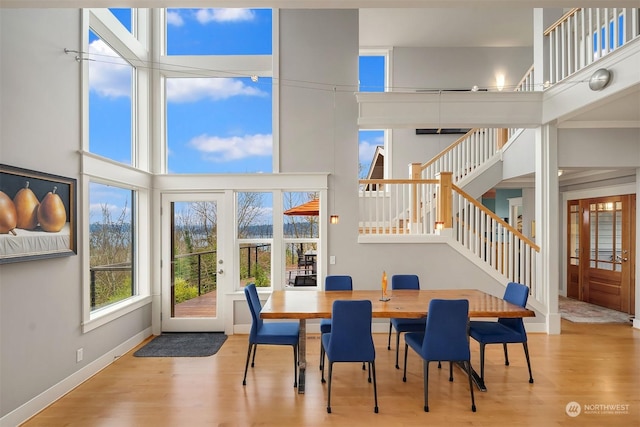 dining space featuring a high ceiling, light hardwood / wood-style flooring, and french doors