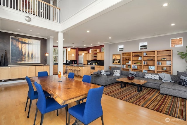 dining space featuring a high ceiling, light hardwood / wood-style flooring, plenty of natural light, and crown molding