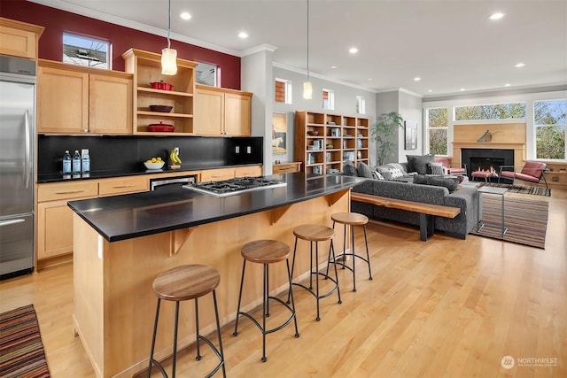 kitchen with appliances with stainless steel finishes, a kitchen bar, light hardwood / wood-style floors, decorative backsplash, and hanging light fixtures