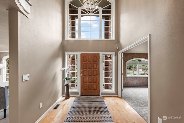 foyer with a chandelier, light hardwood / wood-style floors, and a high ceiling