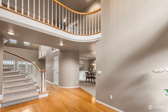 stairs with hardwood / wood-style floors and a high ceiling