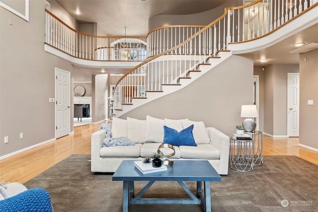 living room featuring an inviting chandelier, wood-type flooring, and a high ceiling