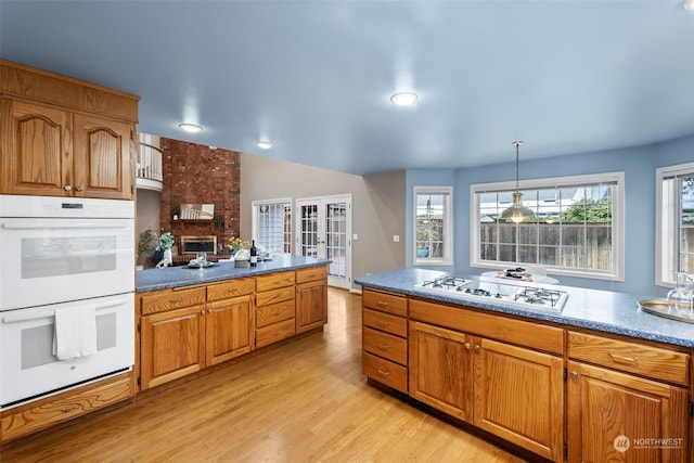 kitchen featuring lofted ceiling, pendant lighting, white appliances, and light hardwood / wood-style floors