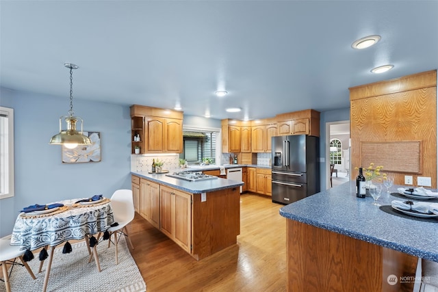 kitchen with high end black fridge, decorative light fixtures, kitchen peninsula, and decorative backsplash