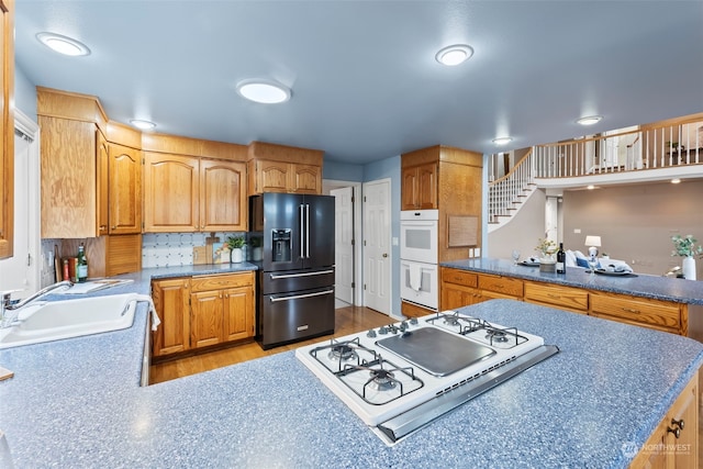 kitchen with sink, white appliances, kitchen peninsula, and backsplash