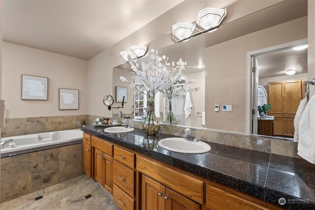 bathroom featuring tiled tub and vanity