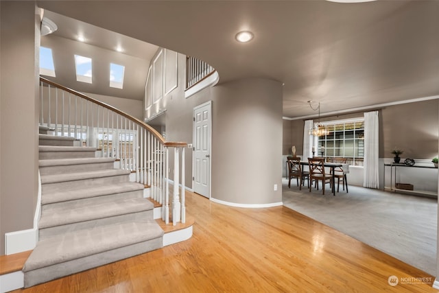 stairs featuring crown molding, wood-type flooring, and a notable chandelier