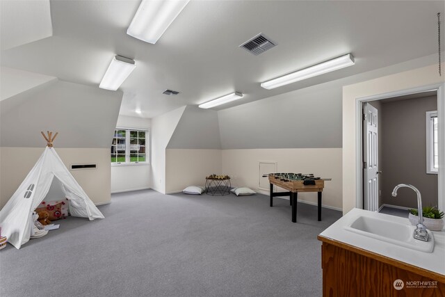 game room with sink, vaulted ceiling, and light colored carpet