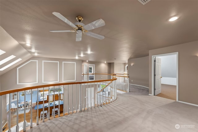 additional living space featuring ceiling fan, light colored carpet, and lofted ceiling with skylight