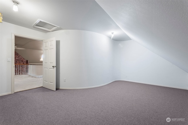 additional living space featuring carpet floors, vaulted ceiling, and a textured ceiling