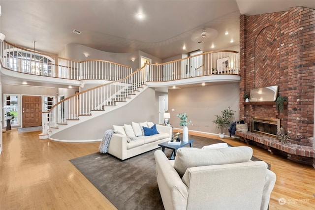 living room featuring hardwood / wood-style flooring, a towering ceiling, and a fireplace