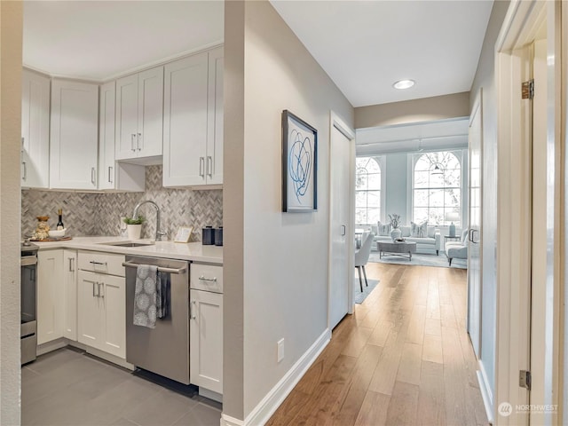 kitchen featuring sink, white cabinetry, stainless steel appliances, tasteful backsplash, and light wood-type flooring