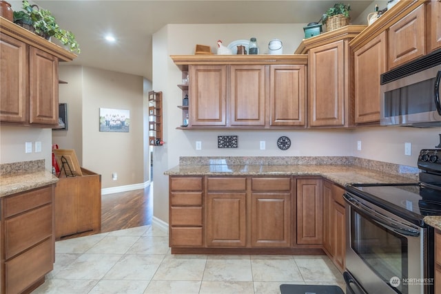 kitchen featuring stainless steel appliances, light tile patterned flooring, and light stone countertops