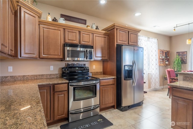 kitchen featuring light tile patterned floors, rail lighting, stainless steel appliances, light stone counters, and decorative light fixtures