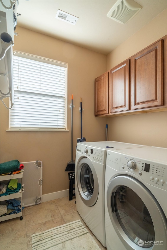 clothes washing area featuring light tile patterned flooring, cabinets, and washing machine and dryer