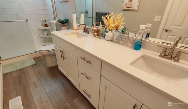 bathroom featuring hardwood / wood-style floors, toilet, walk in shower, and vanity