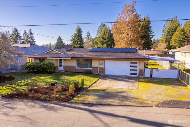 ranch-style home with a garage, a front yard, and solar panels