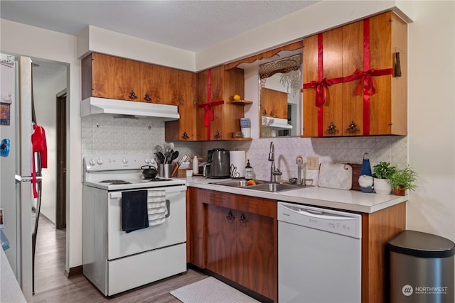 kitchen featuring light hardwood / wood-style floors, sink, white appliances, and backsplash