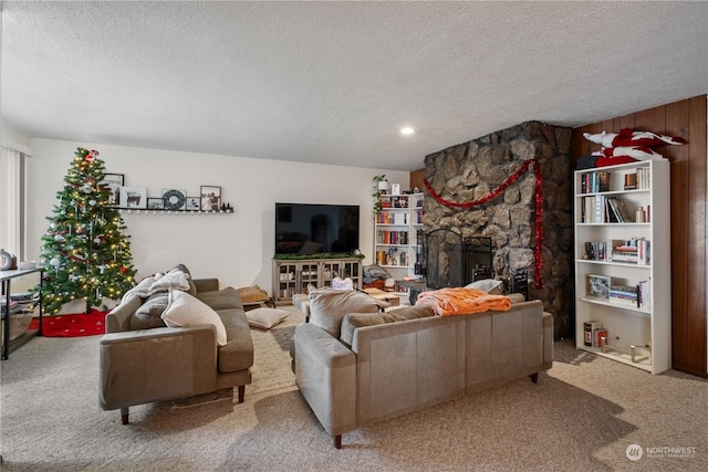 living room featuring a fireplace, wood walls, a textured ceiling, and carpet floors