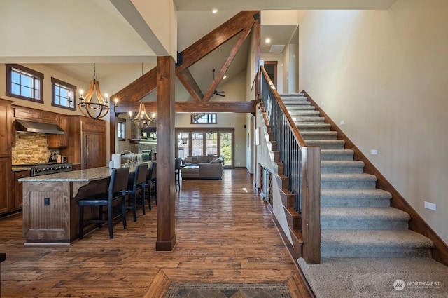 interior space featuring a towering ceiling, a chandelier, hanging light fixtures, a breakfast bar, and light stone counters