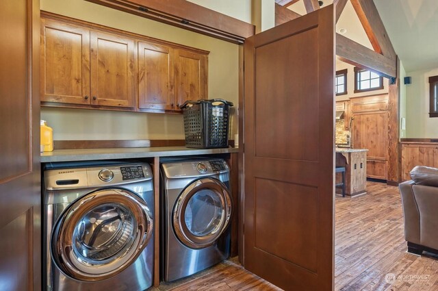 laundry room with wood walls, cabinets, hardwood / wood-style flooring, and washing machine and clothes dryer