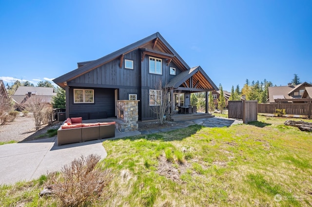 back of house with an outdoor living space, a patio, and a lawn