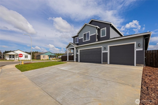 view of front facade with a garage, driveway, and fence