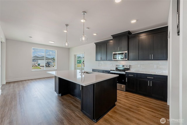 kitchen with stainless steel appliances, light countertops, a sink, and wood finished floors