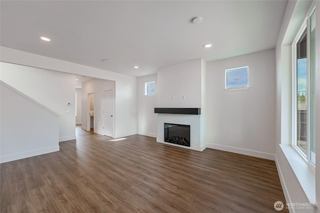 unfurnished living room featuring a healthy amount of sunlight, a fireplace, wood finished floors, and recessed lighting