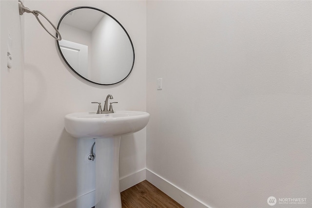 bathroom with a sink, baseboards, and wood finished floors