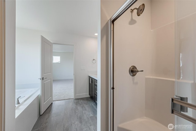 full bath featuring wood finished floors, a shower stall, vanity, and a bath