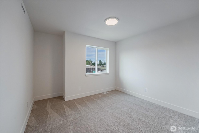 carpeted spare room with visible vents and baseboards