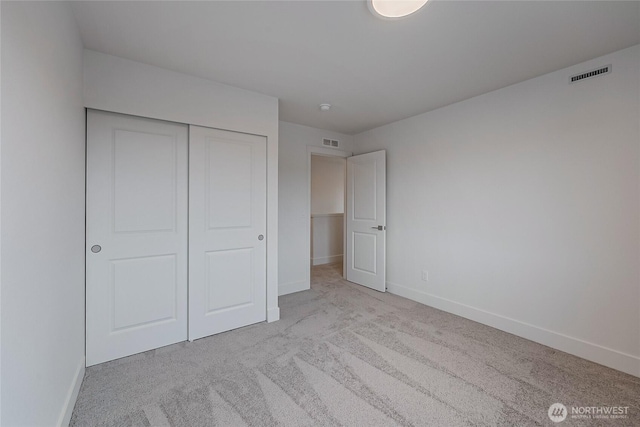 unfurnished bedroom with carpet floors, a closet, visible vents, and baseboards