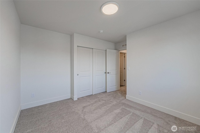 unfurnished bedroom with a closet, carpet flooring, visible vents, and baseboards