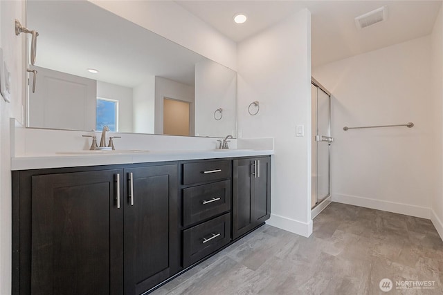 bathroom featuring a stall shower, a sink, visible vents, and baseboards