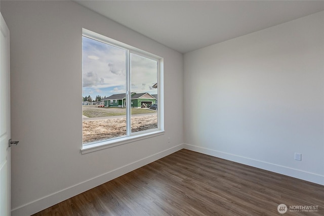 unfurnished room with dark wood finished floors and baseboards