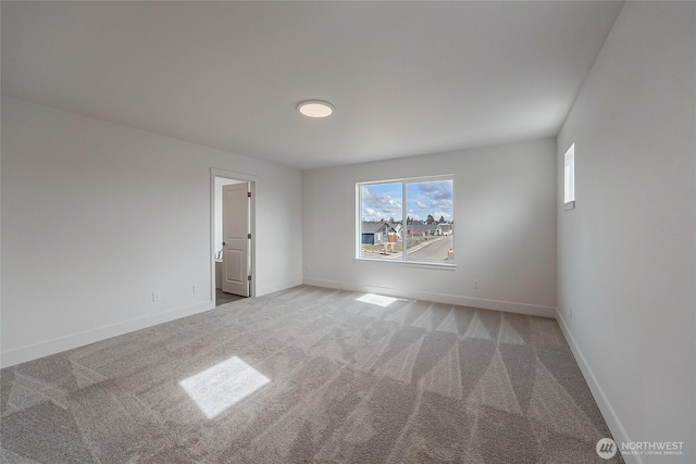 carpeted spare room featuring baseboards