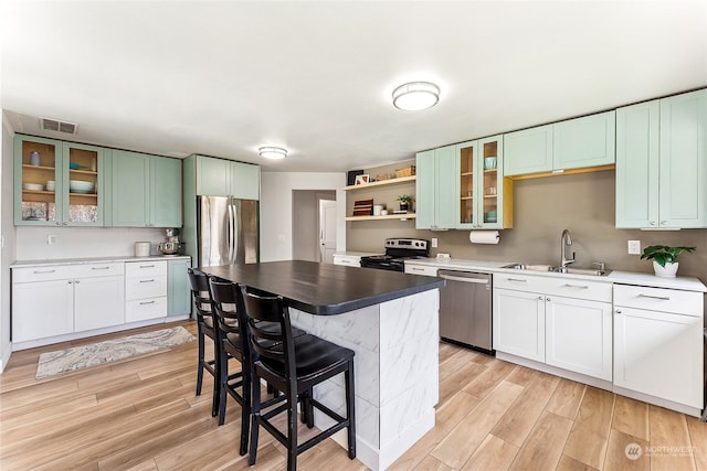 kitchen featuring stainless steel appliances, light wood-type flooring, a sink, and open shelves