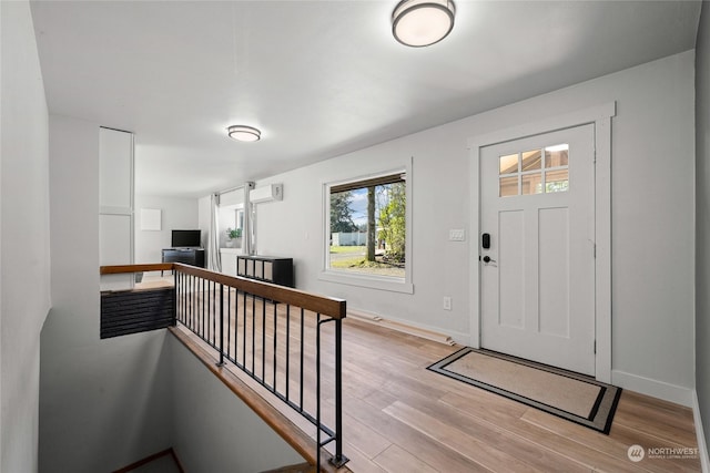 entrance foyer with light wood finished floors, baseboards, and a wall mounted AC