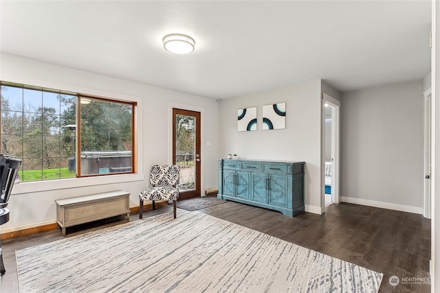 living area with a wealth of natural light, baseboards, and dark wood-type flooring