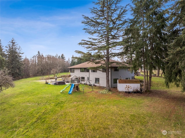 back of house featuring a playground and a yard