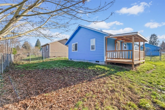 rear view of house with a wooden deck and a lawn